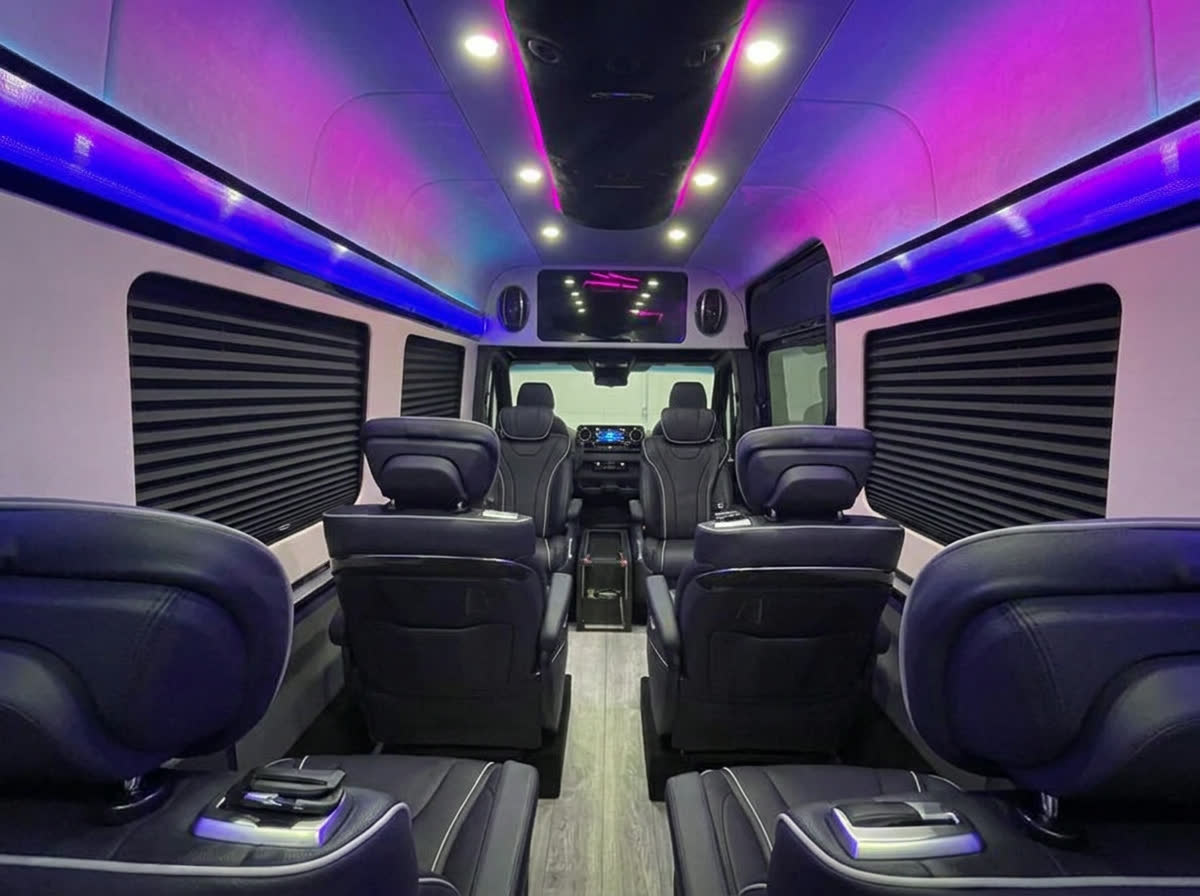 Sprinter van cabin with reclining leather captain's chairs and purple and blue LED lighting