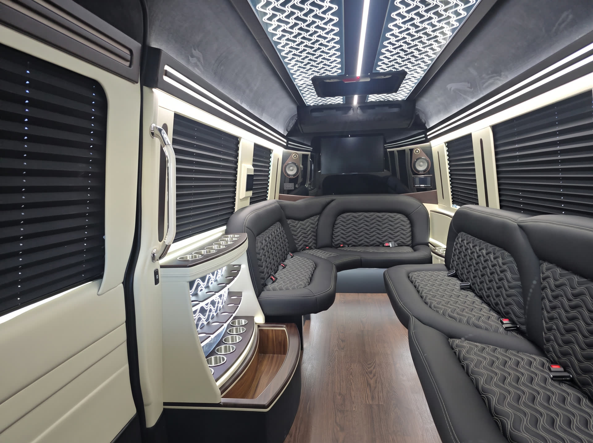 Sprinter limousine lounge interior with wraparound leather seating, illuminated bar and hardwood floor