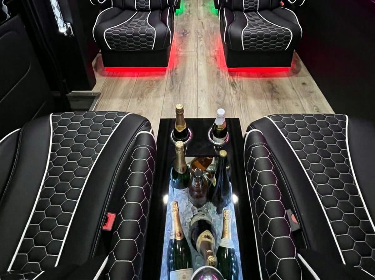 Honeycomb-stitched limo seating facing a glass-top ice chest filled with champagne