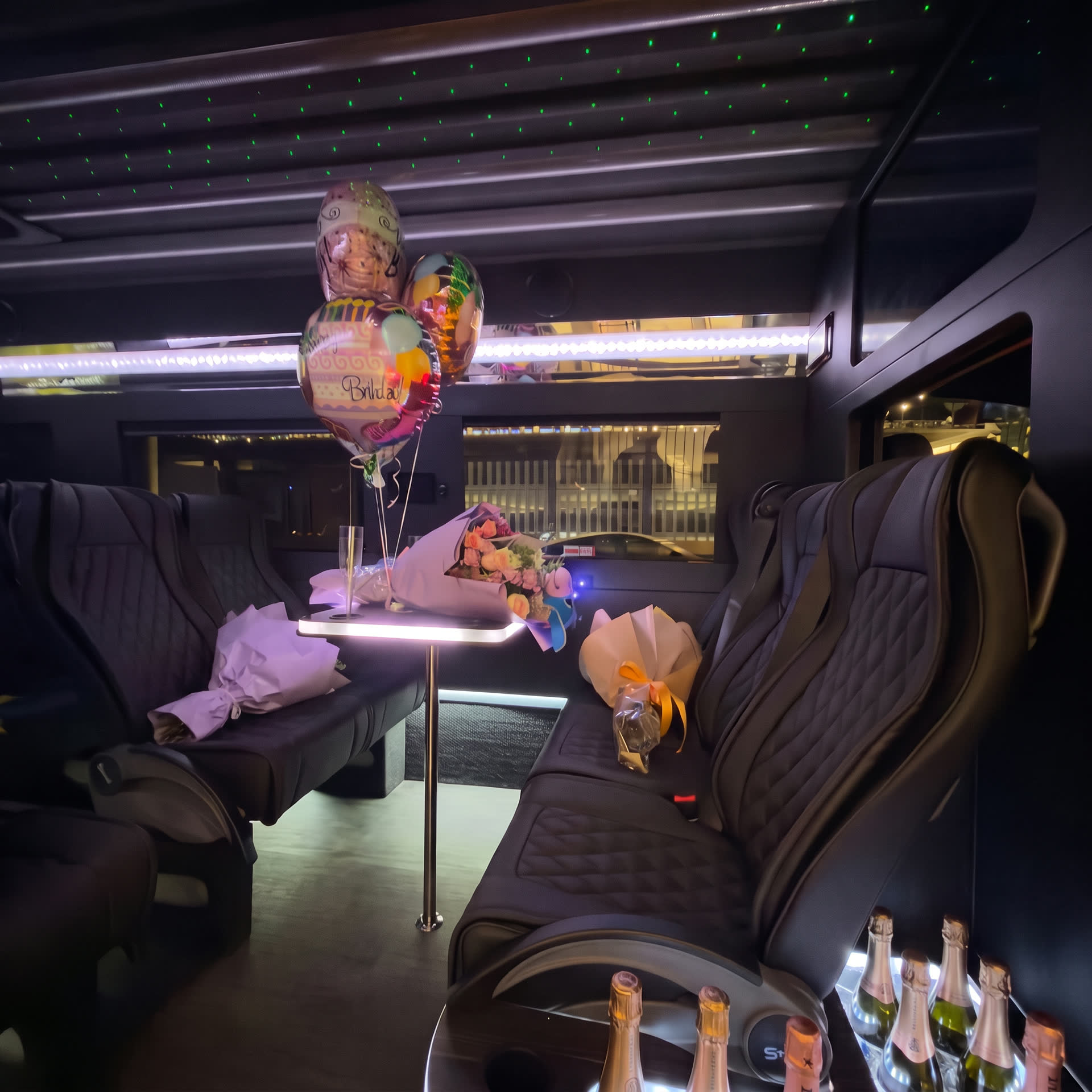 Party van interior decorated with balloons, flowers and champagne under a starlight ceiling
